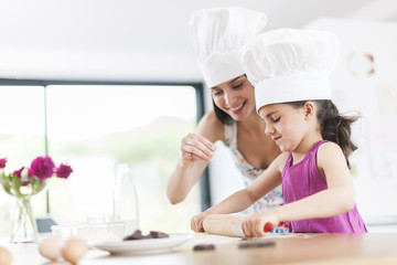 little girl helping her mother prepare a cake