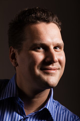 Portrait of young man in blue shirt on dark gray