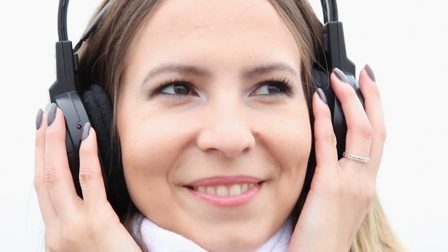 Happy flirty girl young woman with headphones listening to music