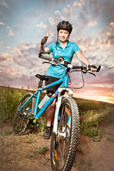 Fototapeta na wymiar Pretty young woman on the bike showing thumb up