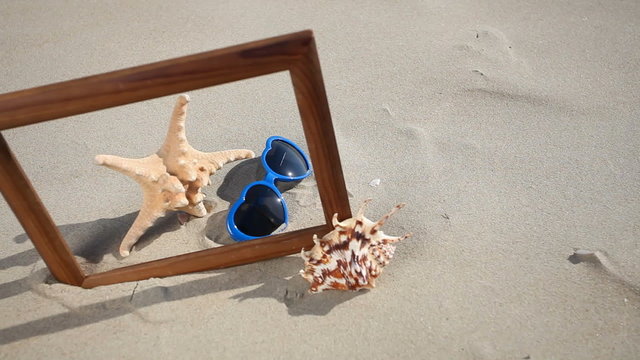 Frame with seashell, starfish and sunglasses on the beach