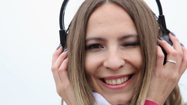 Happy flirty girl young woman with headphones listening to music