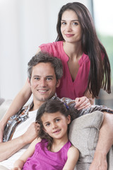 smiling family on a couch looking at camera