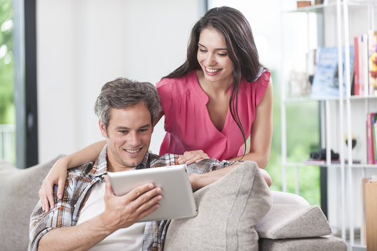 handsome couple using digital tablet on a couch