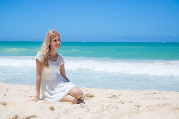 Fototapeta na wymiar Smiling young girl sitting on the sandy beach