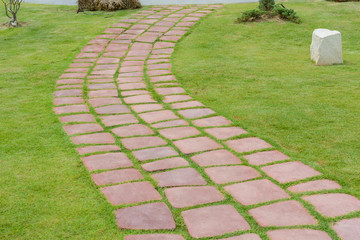 Stone walk path in the park with green grass