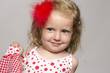 Little adorable blonde girl with a red flower in hair smilling