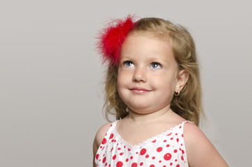 Little adorable blonde girl with a red flower in hair smilling