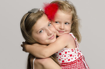 Girl holding in her arms, kissing and having fun with her sister