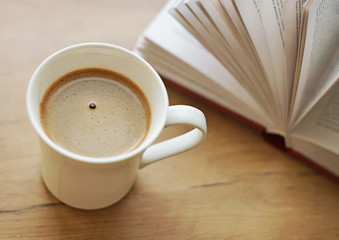 Freshly brewed coffee cup against book.