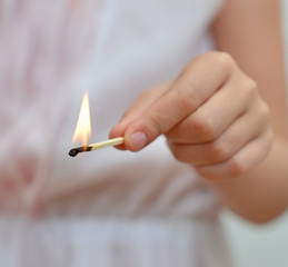 Girl playing with match. Dangerous situation at home.