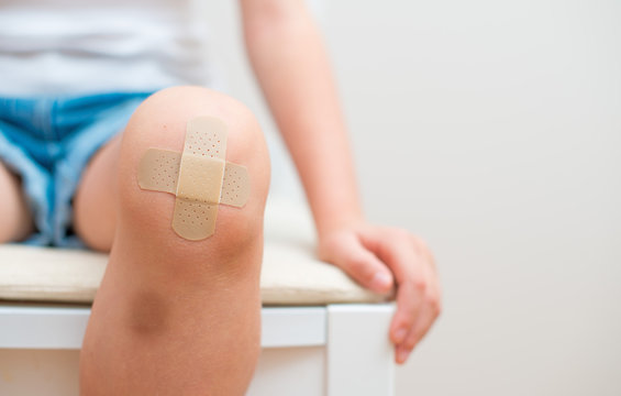 Child knee with an adhesive bandage and bruise.