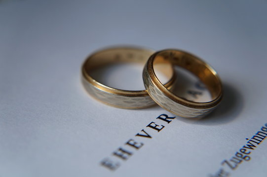 Nahaufnahme zwei Eheringe und ein Ehevertrag