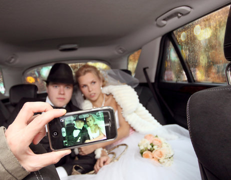 bride and groom are photographed on phone