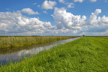 Obraz premium Chmury nad kanałem przez wiejski krajobraz