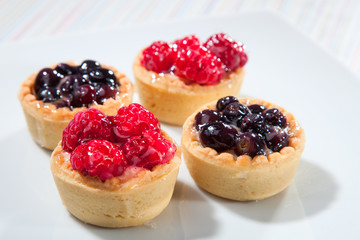 Group of tarts with raspberries and blueberries on white backgro