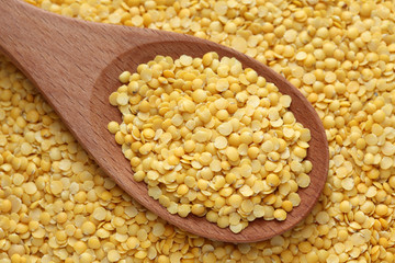 Yellow lentils in a wooden spoon