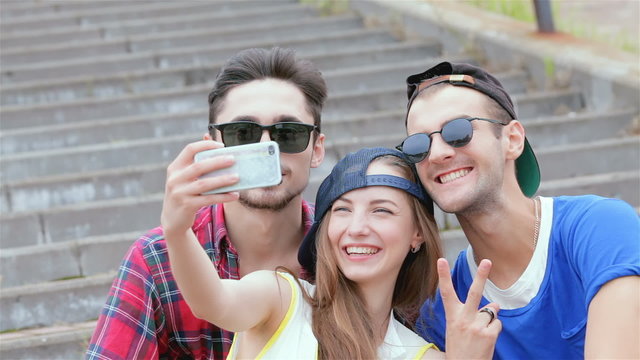 Cheerful girl sitting on the steps of his friends makes selfie