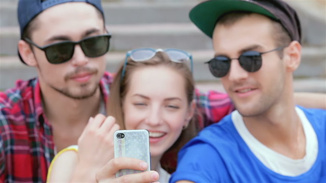 Cheerful girl sitting on the steps of his friends makes selfie