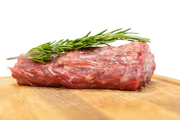 raw steak with rosemary on wood plate