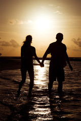 Silhouette of a young couple at sunset near the shore of the oce