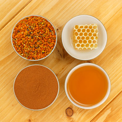 Honey, honeycomb, pollen and cinnamon in bowls