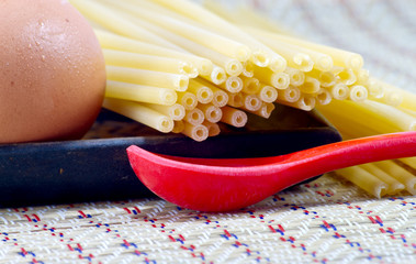 Egg with spaghetti on a wood with red plastic spoon