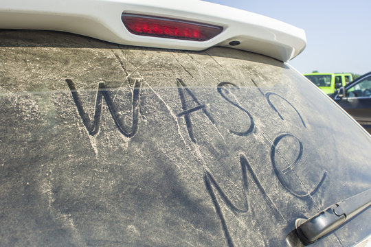 Dirty rear window of the car and inscription Wash me