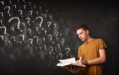 Young man reading a book with question marks coming out from it