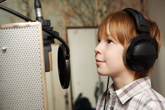 redhead boy standing in front of a microphone with headphones