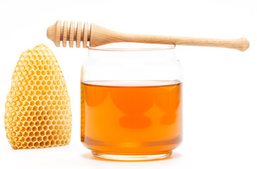 Honey in jar with dipper and honeycomb on isolated background