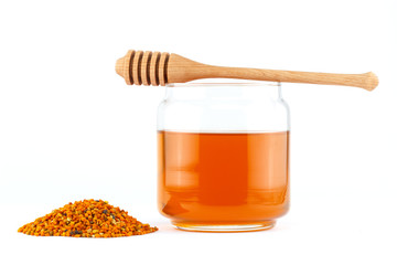 Honey in jar with dipper and pollen on isolated background