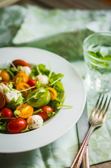 Salad with arugula,tomatoes and mozarella on wooden background