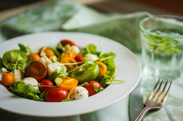 Salad with arugula,tomatoes and mozarella on wooden background