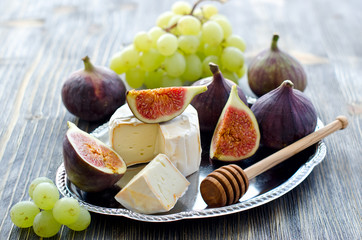 Delicious snack cheese, figs and grapes. Wooden background