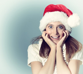 Portrait of surprised attractive cheerful girl in Santa's hat ha