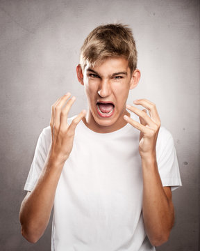 young man screaming on a grey background