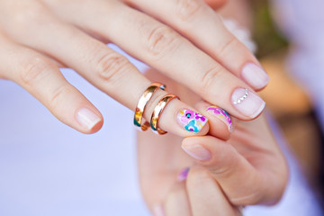 Wedding ring on the finger of a bride with a colored nail polish