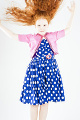 Happy Jumping Red-haired Caucasian Girl In Polka-Dotted Dress Pl