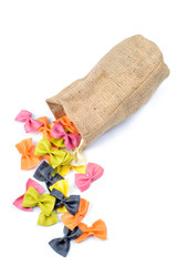 Multicolored farfalle falling from canvas bag