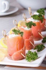 Finger food. Rolls of salmon closeup on the table vertical
