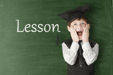 Cheerful little boy on blackboard. Looking at camera