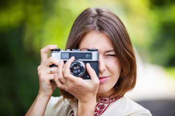 Young woman taking picture with retro camera outdoors