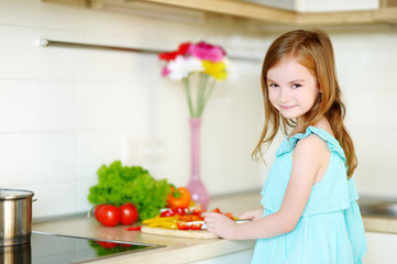 Little girl helping her mother in a kitchen