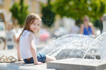 Cute girl playing with a city fountain