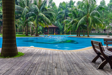 Swimming pool with hut and wooden pool deck in garden of resort