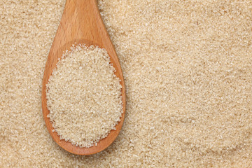 Brown cane sugar in a wooden spoon