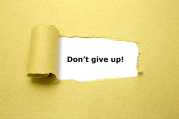 Don't Give Up! appearing behind torn brown paper