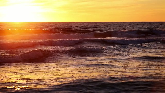 Evening sea waves at sunset in orange sunset