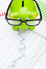 Green piggy bank over stock market chart - view from top